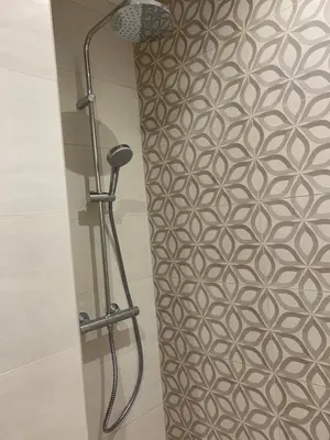a shower in a bathroom with a patterned wall at Agréable 2 pièces à 150 m de la mer in Cagnes-sur-Mer