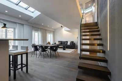 a living room with a staircase and a table with chairs at Duplex Nice Avenue Jean-Médecin in Nice