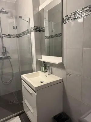 a white bathroom with a sink and a shower at Bas de Villa à 15 min de Nice avec piscine in Carros
