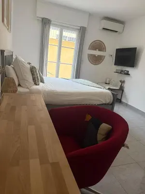 a bedroom with a bed and a red chair at Bas de Villa à 15 min de Nice avec piscine in Carros