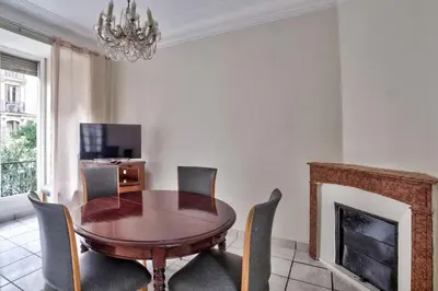 a dining room with a table and chairs and a fireplace at Nidusudest - Spacieux appartement in Nice