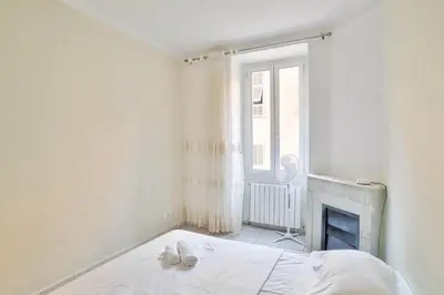 a white bedroom with a bed and a fireplace at Nidusudest - Spacieux appartement in Nice