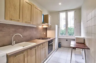 a kitchen with wooden cabinets and a sink and a window at Nidusudest - Spacieux appartement in Nice