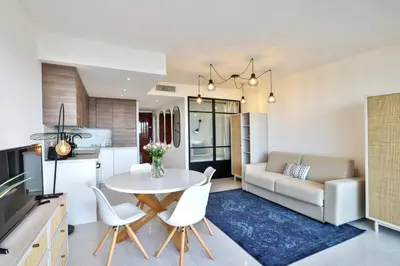 a kitchen and living room with a table and chairs at Incroyable vue mer, 2 pièces refait à neuf avec piscine sur le toit/ WIFI/AC in Nice