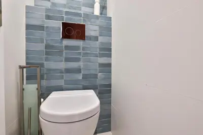 a bathroom with a toilet with blue tiles at Incroyable vue mer, 2 pièces refait à neuf avec piscine sur le toit/ WIFI/AC in Nice