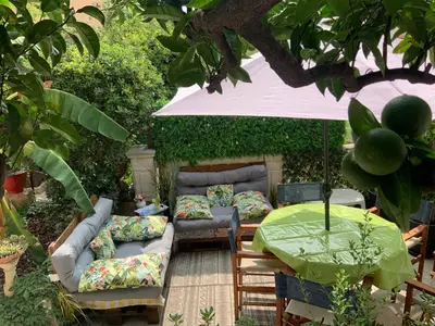 a patio with couches and a table with a green umbrella at Douceur d'Azur in Nice