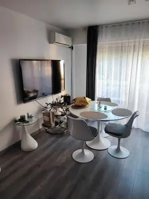 a living room with a table and chairs and a television at Studio 31 m² in Nice
