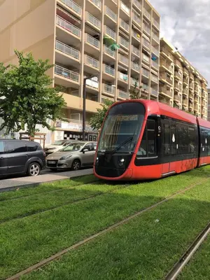a red tram on the grass in front of a building at Promenade des anglais 20 mètres in Nice