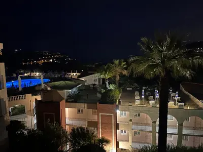 a view of a building at night with palm trees at Pool , 150m to beach, seaview in Villefranche-sur-Mer