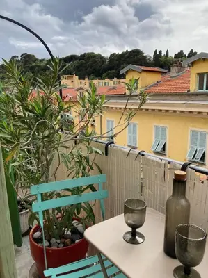 a table with a bottle and a chair on a balcony at Charmant deux pièces dans le quartier du Port in Nice