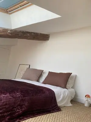 a white bedroom with a large bed with brown pillows at Charmant deux pièces dans le quartier du Port in Nice
