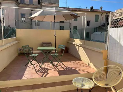 a balcony with a table and chairs and an umbrella at AMAZING STUDIO - GRANDE TERRASSE - COEUR DE VILLE - WIFI - AC in Nice