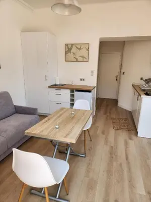 a living room with a wooden table and white chairs at AMAZING STUDIO - GRANDE TERRASSE - COEUR DE VILLE - WIFI - AC in Nice