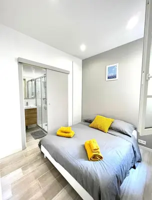a bedroom with a bed with yellow pillows on it at Congrès Résidence in Nice
