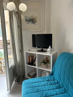 a living room with a tv and a blue couch at Studio lumineux avec balcon à proximité de la mer in Nice