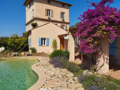 a building with a swimming pool and a tree with purple flowers at L'Albizia in Nice