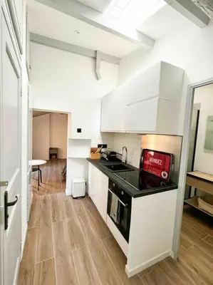 a kitchen with white cabinets and a black counter top at Beautiful Top Floor & Terrasse (Beach 1' walk) in Nice