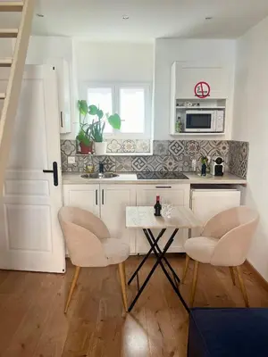 a kitchen with white cabinets and a table and chairs at Le ruisseau in Nice