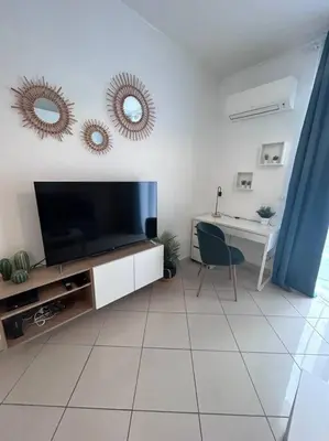 a living room with a flat screen tv and a desk at Studio dans villa proche mer in Nice