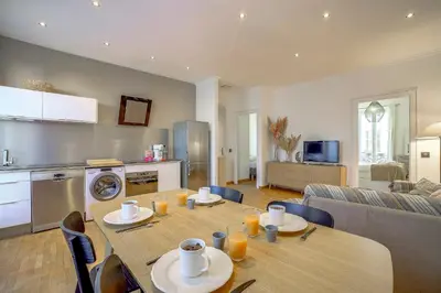 a kitchen and living room with a wooden table and chairs at Maison Bianchi - Chauvain Place Massena in Nice