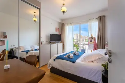 a bedroom with two beds and a table and a window at LE FRANCE AP4350 By Riviera Holiday Homes in Nice