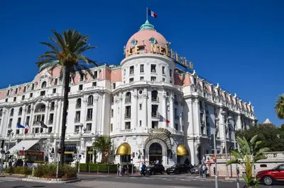 a large white building with a palm tree in front of it at Le GRAND JEAN - CENTRAL PRES GARE ET TRAM - supermarchés - WIFI - 3 Person in Nice