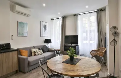 a dining room table with chairs and a wooden table with glasses at Appartement coeur du vieux Nice in Nice