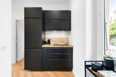 a kitchen with black cabinets and a stove at Nice Renting - MAETERLINCK - Idyllic Luxury Retreat in Cap de Nice Sea View in Nice