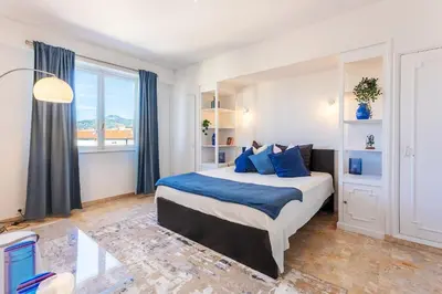 a bedroom with a large bed with blue pillows at PLAZA TERRACE AP4065 by RIVIERA HOLIDAY HOMES in Nice