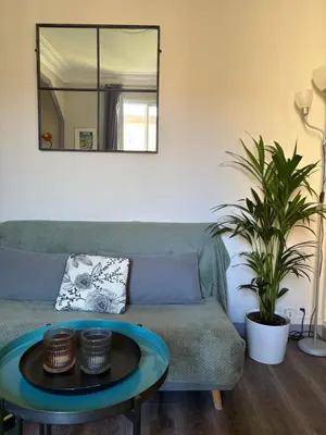 a living room with a couch and a table at Charming studio overlooking a beautiful garden in Nice