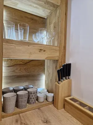 a wooden cabinet with glasses and bowls and utensils at Cosy Haven 5 min from Nice Carnival Hyper-Center! in Nice