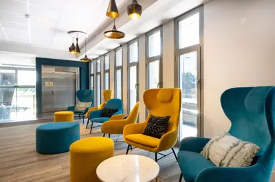 a waiting room with chairs and tables and windows at Nemea Appart Hotel Nice Arenas Aéroport in Nice