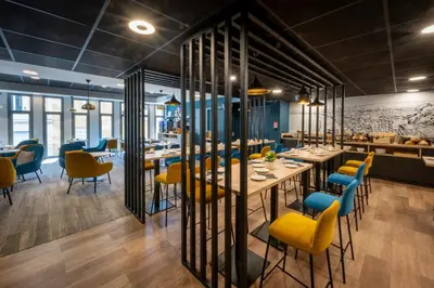 a restaurant with wooden tables and yellow chairs at Nemea Appart Hotel Nice Arenas Aéroport in Nice