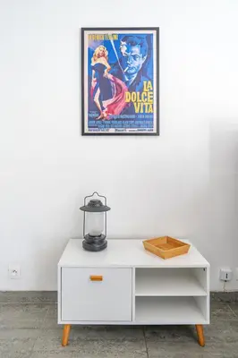 a white dresser with a movie poster on a wall at Le calme à Nissa la Bella in Nice