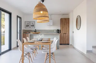 a dining room with a wooden table and white chairs at Villa Riviera - Nouveaute entre mer et montagnes in Colomars