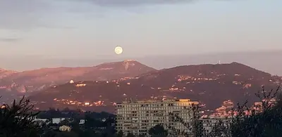 a moon over a city with a building and mountains at Chez Roland in Nice