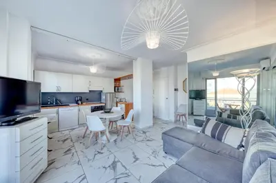 a living room with a blue couch and a kitchen at FAMILY APARTMENT SEA VIEW in Nice