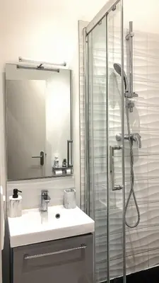 a bathroom with a sink and a shower with a mirror at Studio meublé in Nice