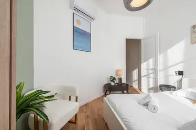 a white bedroom with a bed and a chair at Lovely 2 Bdr Nice Harbor in Nice