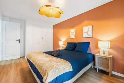 a bedroom with a blue bed and an orange wall at NICE RENTING - PHILIBERT - Elegant Spacious Quiet Near the Port Free Parking in Nice