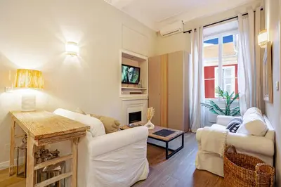 a living room with white furniture and a fireplace at Elegant flat with AC, heart of old Nice, Walking to the Beach! in Nice