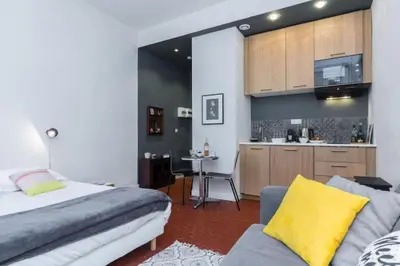 a bedroom with a bed and a table and a kitchen at MY CASA - DROITE - Bright studio in the Old Town in Nice