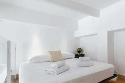 a white bedroom with a large bed with towels on it at MY CASA - DELOYE - Spacious Quiet studio w AC near Old Town in Nice