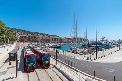 two red trains are parked on the tracks near a marina at MY CASA - MOULIN - Stunning 1 bedroom Apt on the Port in Nice