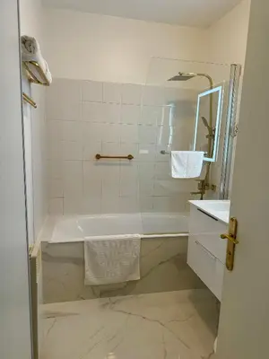 a white bathroom with a tub and a sink at L'appartement Azur in Nice