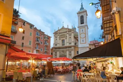 a street with tables and chairs and a clock tower at Magenta - T2 Au Cœur Du Carré D'or De Nice in Nice
