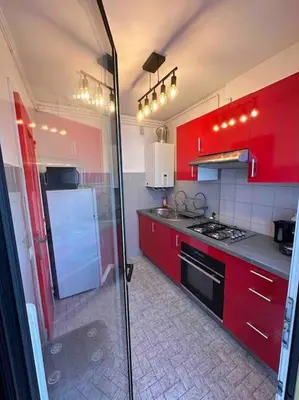 a kitchen with red cabinets and a stove top oven at Orangers - Bord de mer - Studio cosy 4 personnes in Cagnes-sur-Mer