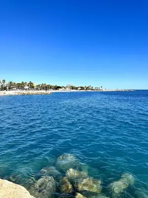 a large body of water with a beach in the background at Orangers - Bord de mer - Studio cosy 4 personnes in Cagnes-sur-Mer