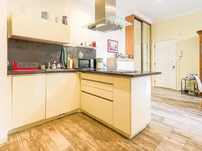 a kitchen with yellow and white cabinets and wood floors at Apartment Terrasses de la Baie des Anges by Interhome in Nice
