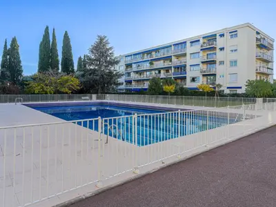 a fence around a swimming pool in front of a building at Apartment Terrasses de la Baie des Anges by Interhome in Nice